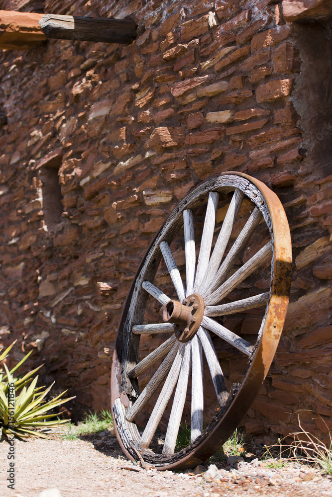Obraz premium Old wheel near a stone wall