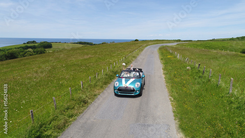 Aerial view of bride and groom driving convertible car in countryside