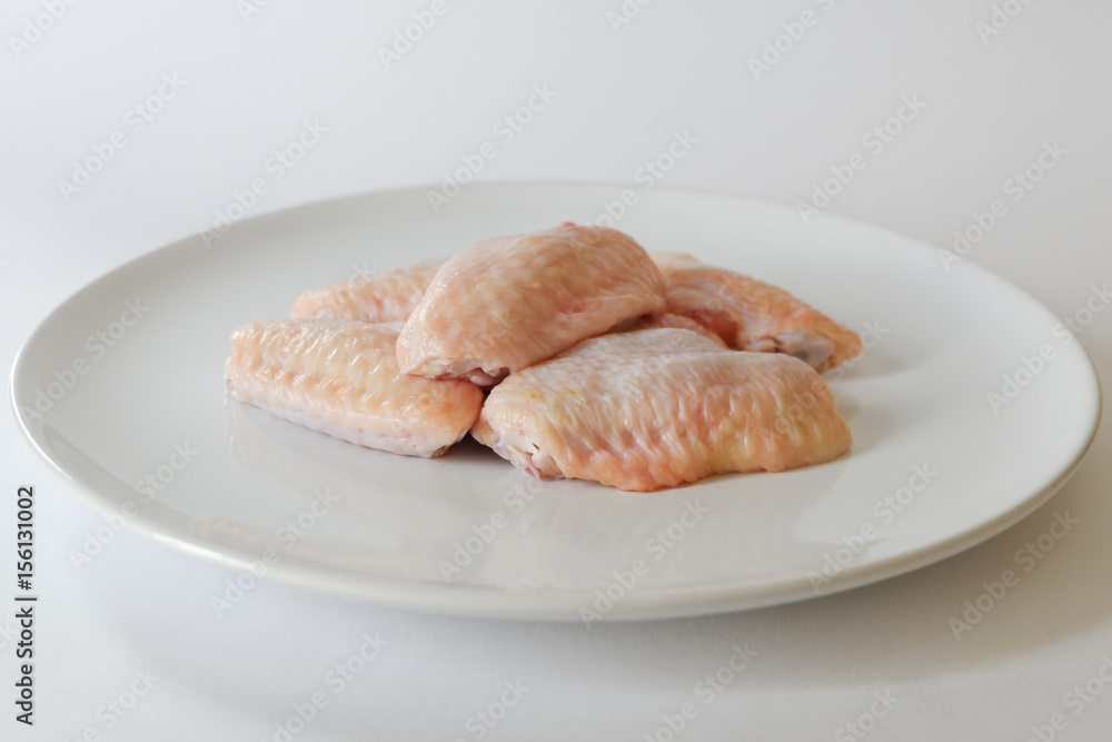 Fresh raw chicken wings on white dish with white background Fresh raw chicken wings on white dish with white background