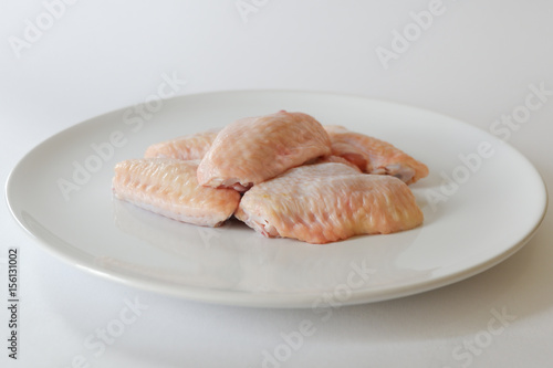 Fresh raw chicken wings on white dish with white background