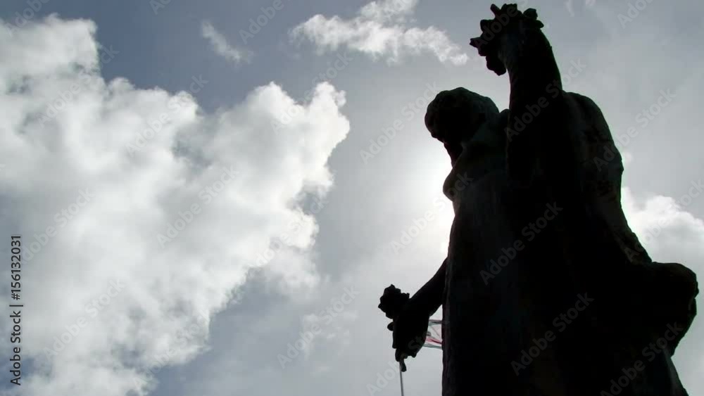Timelapse of white clouds passing over the silhouette of a statue in Willemstad, Curacao Timelapse of white clouds passing over the silhouette of a statue in Willemstad, Curacao