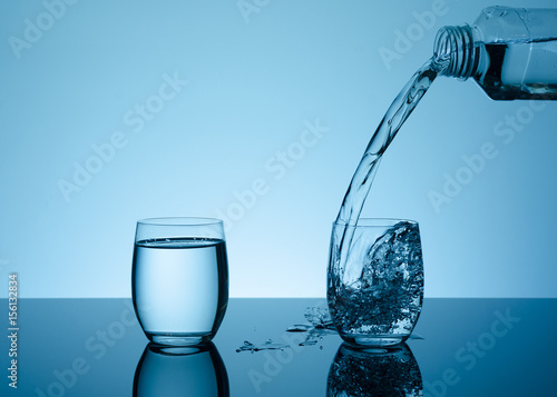 Bottle with creative splashing water in the glass