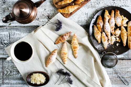 Homemade breakfast with fresh pastries. Many croissants with sugar powder and almonds, top view photo