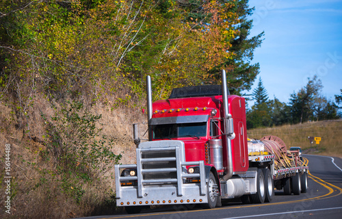 Konstfotografi Red powerful big rig semi truck and step deck trailer with cargo