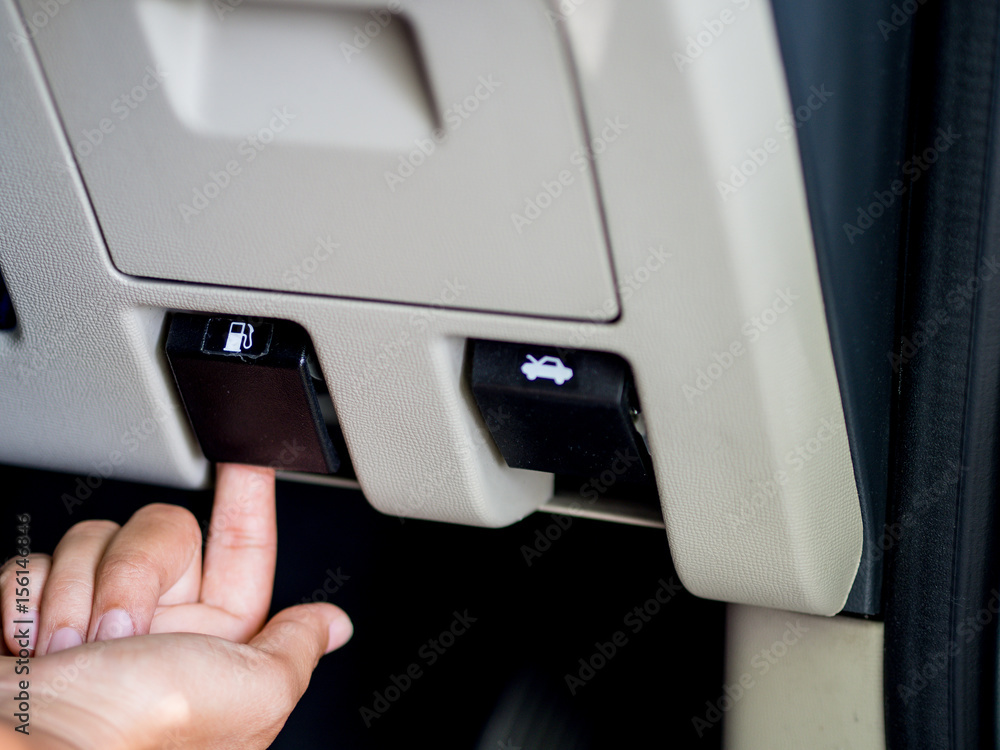 Hand holding a Switch for opening the fuel tank inside the vehicle Hand holding a Switch for opening the fuel tank inside the vehicle