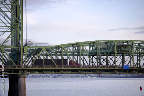 Arched section of bridge with support and moving red semi truck black trailer photo