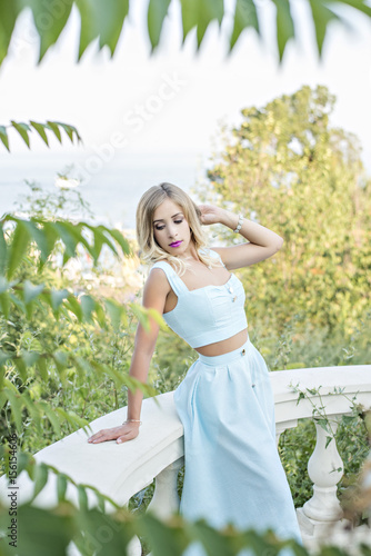 Vintage girl in a turquoise skirt on a white beautiful staircase