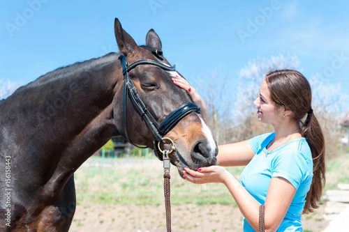 Rest after training. Lady owner scratching her favorite horse nose