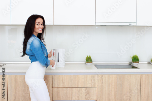 adult brunette awoman making tea on kitchen room interior