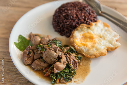 Spicy fried chicken innards with basil leaves served with fried egg and rice berry,Thai style food