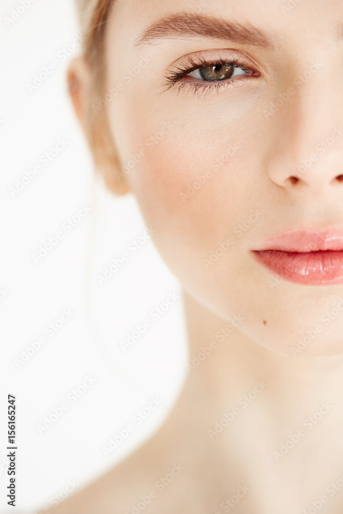 Half face portrait of young beautiful girl with clean fresh skin looking at camera over white background. Beauty and health lifestyle. Half face portrait of young beautiful girl with clean fresh skin looking at camera over white background. Beauty and health lifestyle.