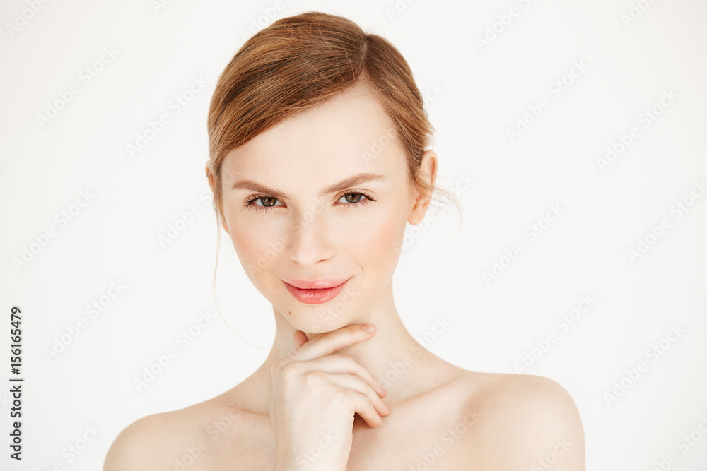 Portrait of young nude beautiful girl smiling looking at camera touching face over white background. Facial treatment. Beauty cosmetology and spa. Portrait of young nude beautiful girl smiling looking at camera touching face over white background. Facial treatment. Beauty cosmetology and spa.