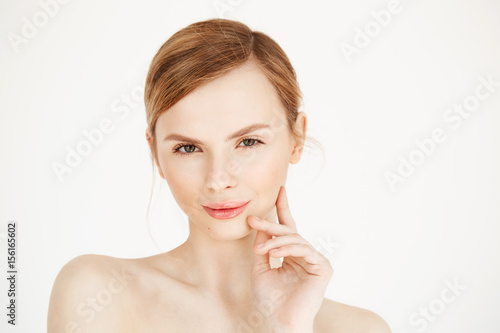 Portrait of young beautiful girl looking at camera touching face over white background. Facial treatment. Beauty cosmetology and skincare.