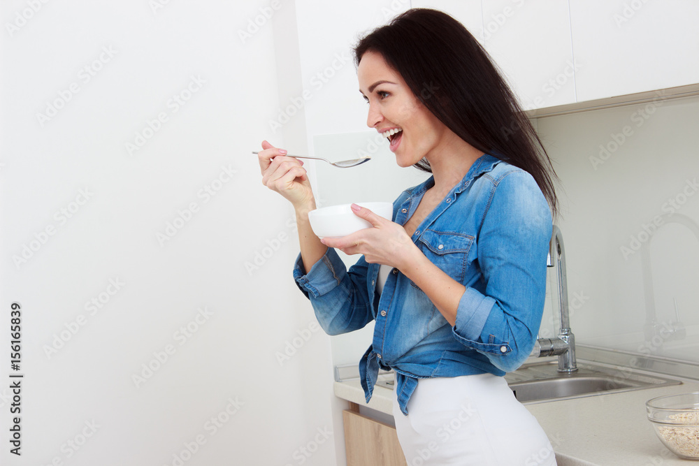 Wellness concept. Beautiful young woman having breakfast and smiling. Healthy eating