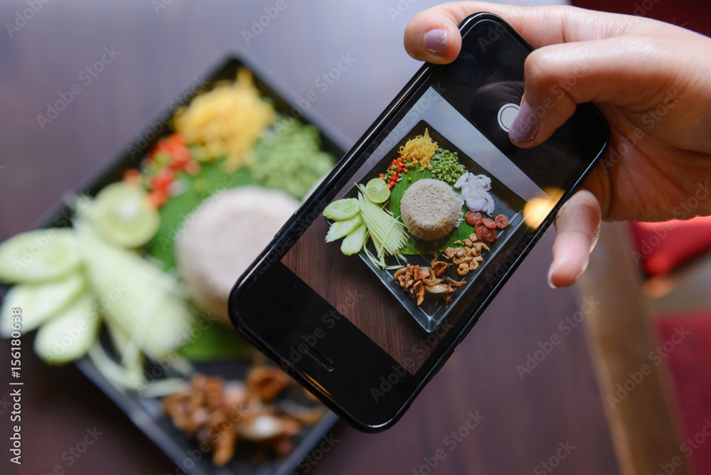 Women user smart phone to take picture of Rice mixed with shrimp paste (Kao Cluk Ka Pi) - obrazy, fototapety, plakaty 