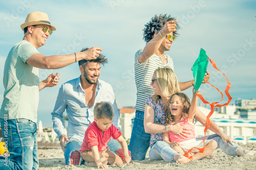 happy family with chldren on beach playing with friends flying a kite photo