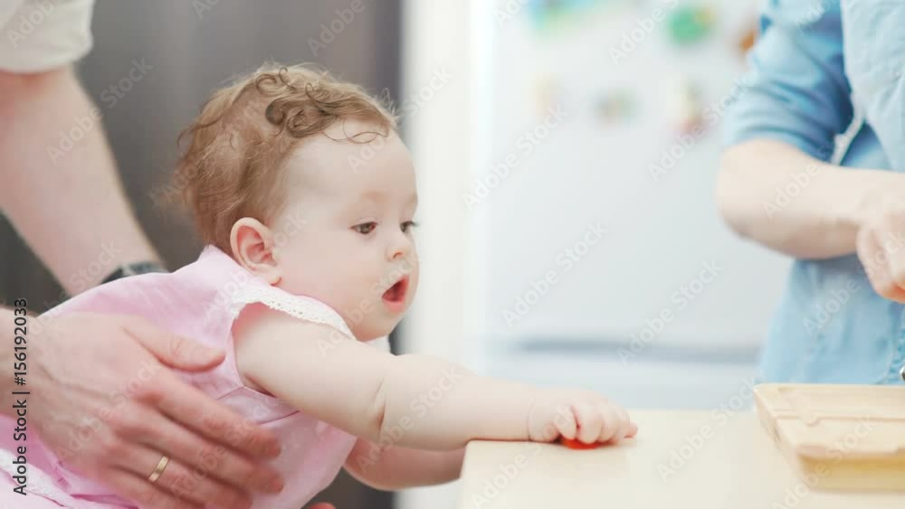 Young and beautiful woman prepares breakfast for her family in a cozy and stylish kitchen, and a small child watches the process with interest. The husband helps his wife and looks after the child. Young and beautiful woman prepares breakfast for her family in a cozy and stylish kitchen, and a small child watches the process with interest. The husband helps his wife and looks after the child.