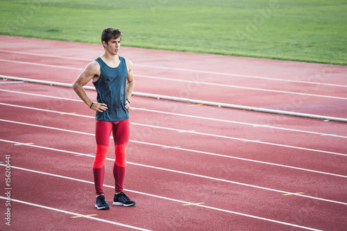 Young athlete standing on race track in stadium photo