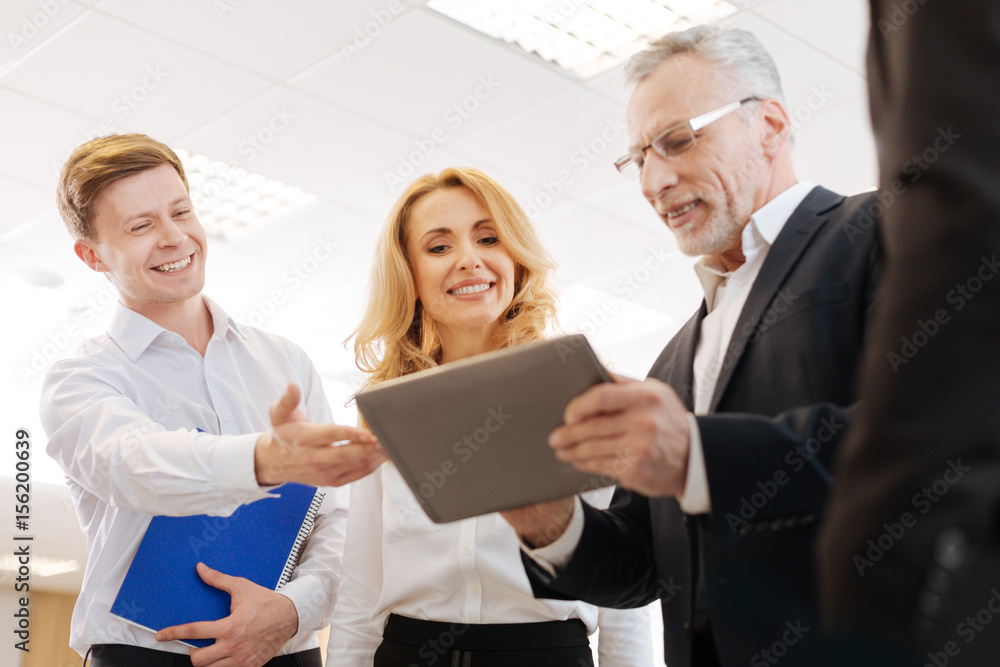 Joyful delighted colleagues looking at the tablet screen