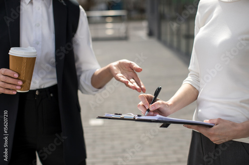 cropped view of two businesswomen on meeting outdoors near office building