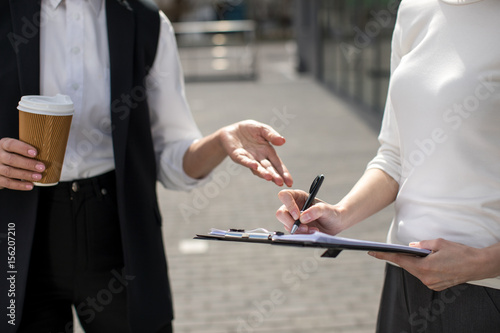 cropped view of two businesswomen on meeting outdoors near office building photo