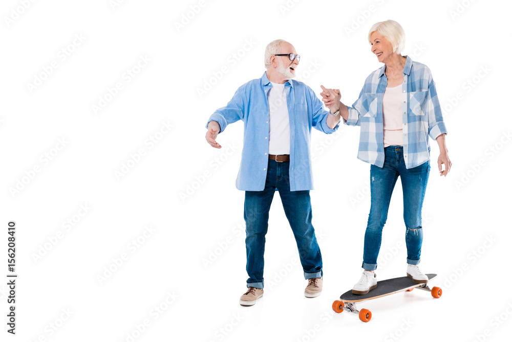 happy senior couple skateboarding and holding hands isolated on white