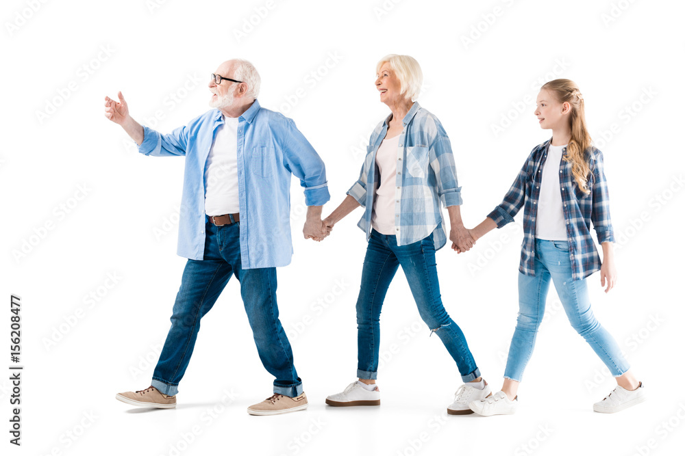 happy grandfather, grandmother and granddaughter walking and holding hands together isolated on white happy grandfather, grandmother and granddaughter walking and holding hands together isolated on white