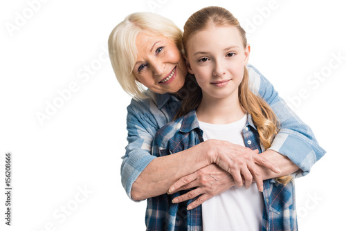 portrait of grandmother and granddaughter embracing isolated on white in studio