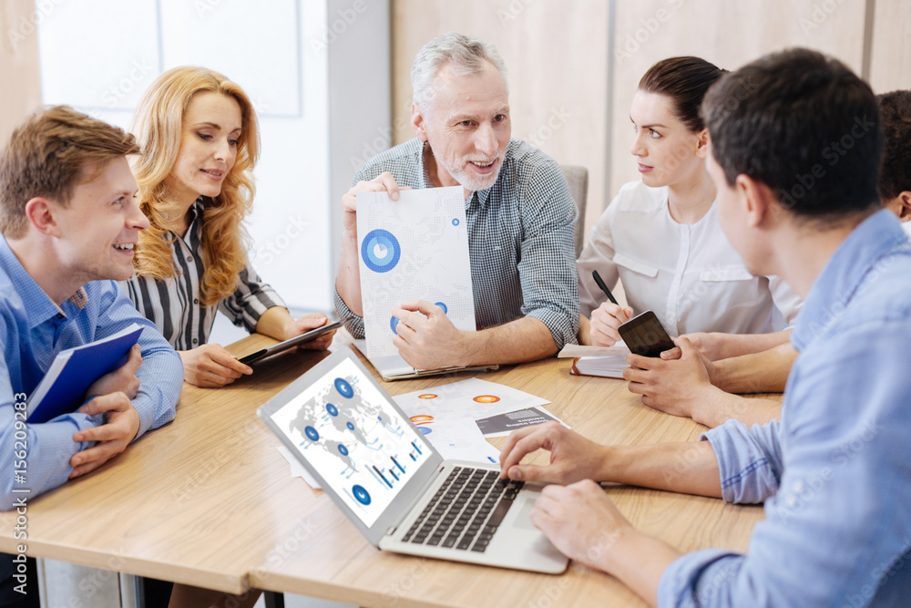 Happy elderly man showing a presentation to his colleagues Happy elderly man showing a presentation to his colleagues
