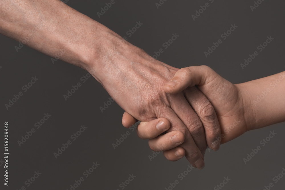 cropped view of people holding hands isolated on grey, young and senior people concept