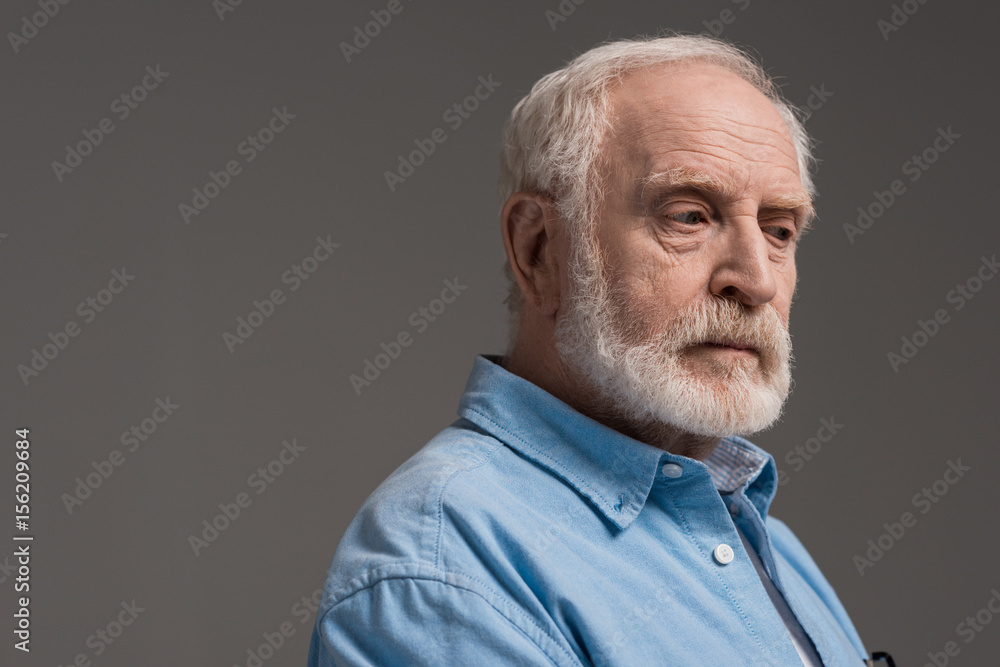 portrait of senior bearded man isolated on grey in studio portrait of senior bearded man isolated on grey in studio