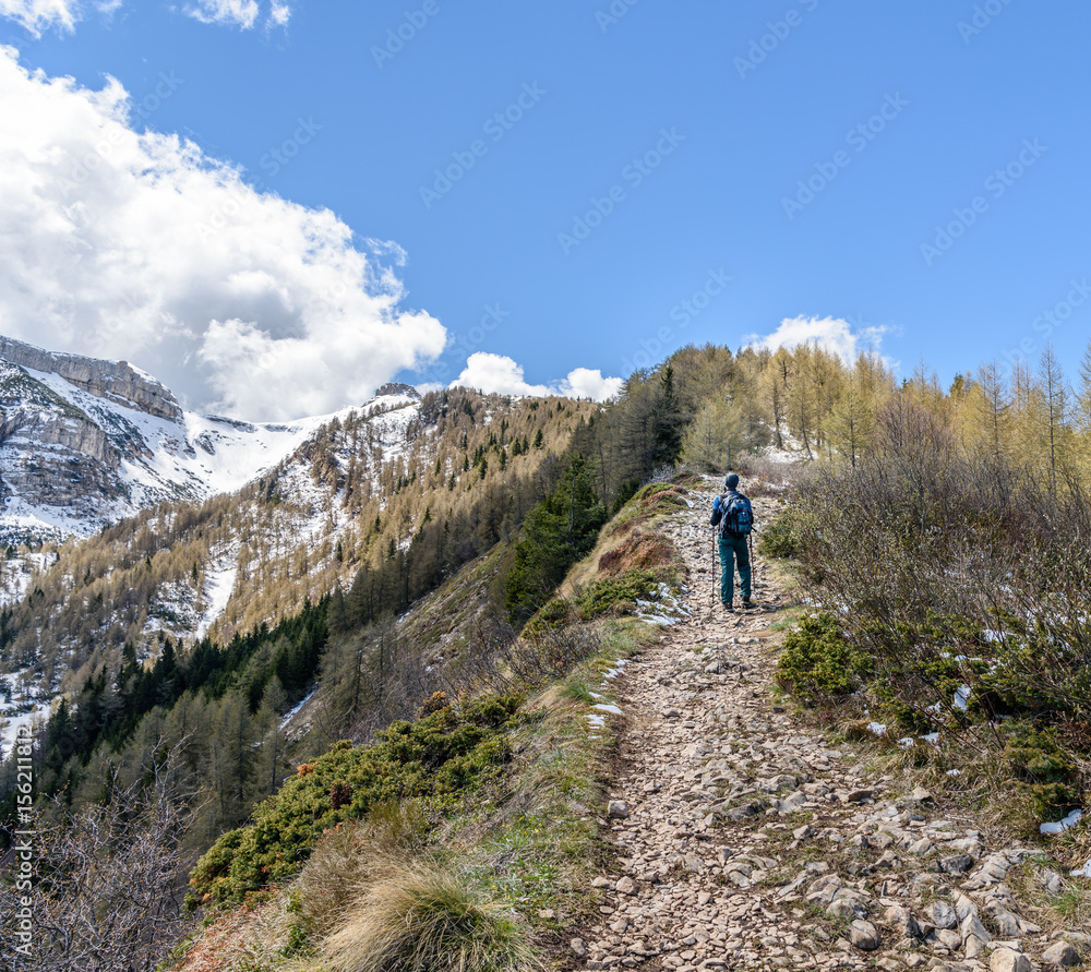 A man with a backpack walk uphill the mountain trail .Hiking health sport lifestyle.