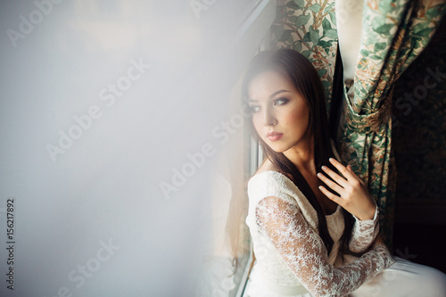 The charming girl sits on the window-sill