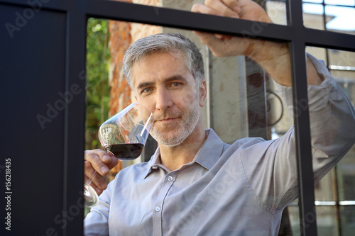 Przystojny mężczyzna w średnim wieku pije wino.
