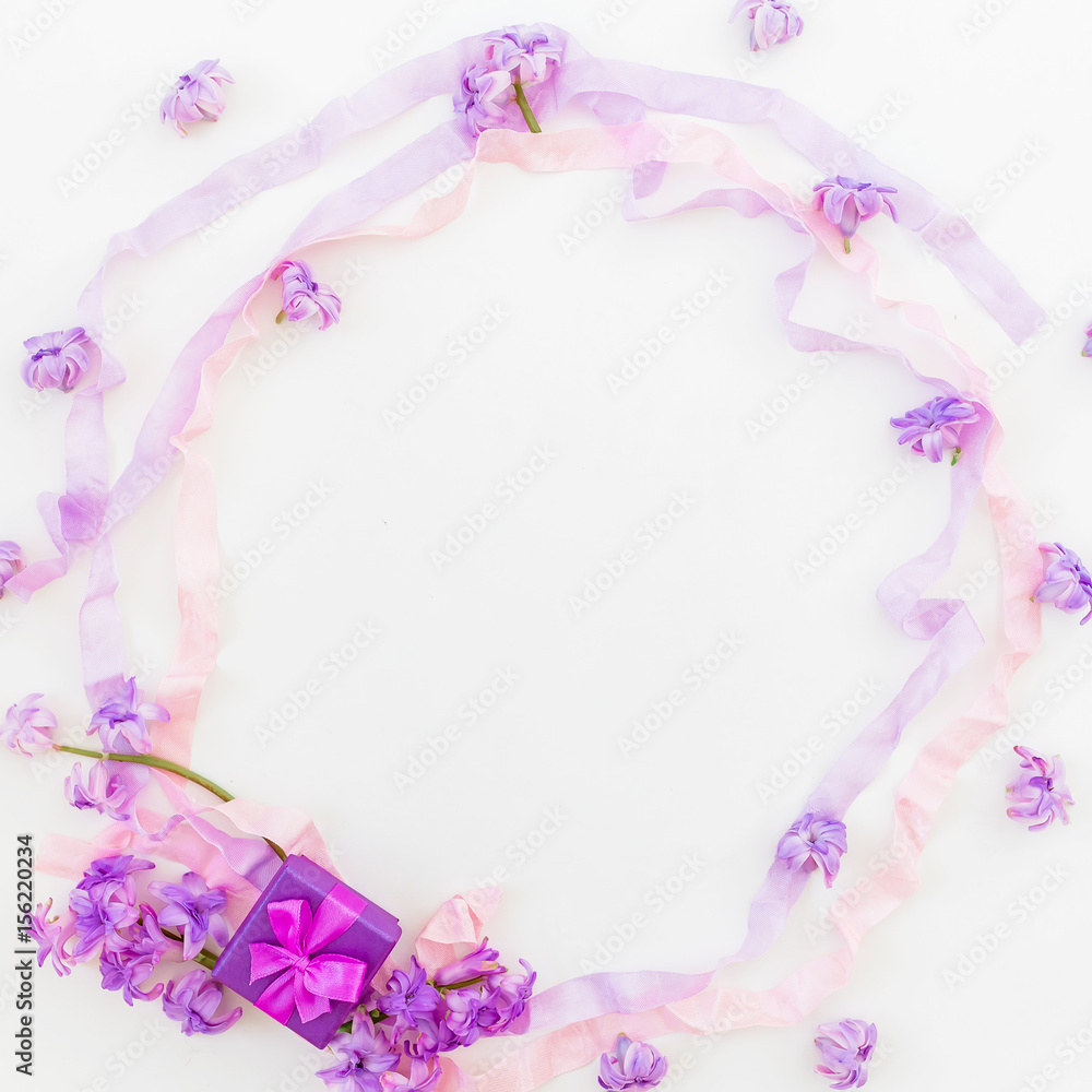 Purple round frame of pink flowers and tapes on white background. Flat lay, top view.
Ring box