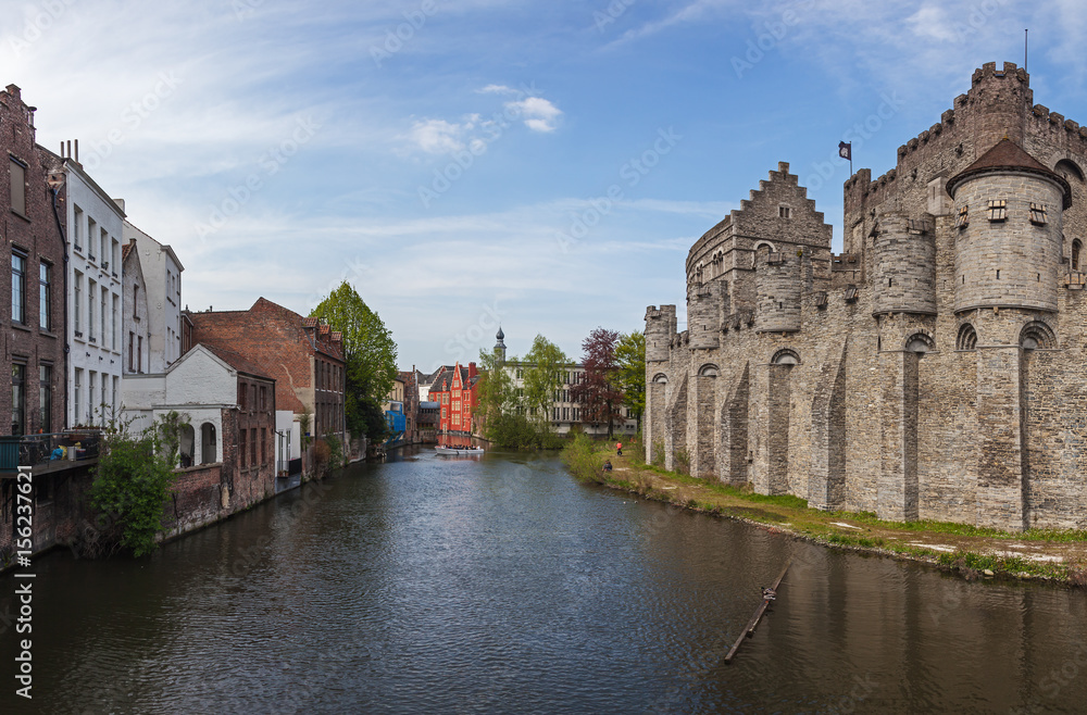 Panoramic view of medieval Gravensteen castle and canal with old picturesque traditional houses in historic part of Ghent, Belgium