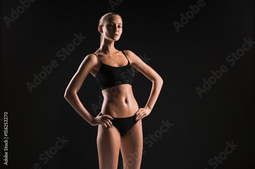 Muscular young woman athlete on black