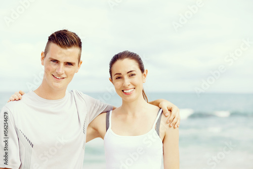 Young couple looking at camera while standing next to each other on beach