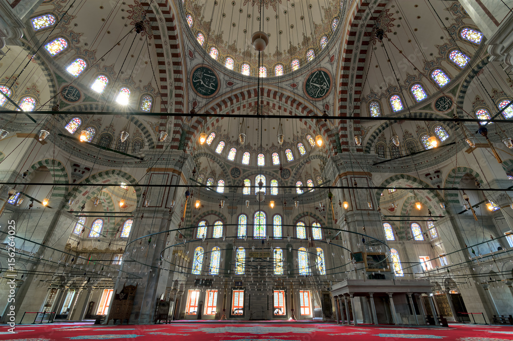 Fatih Mosque, a public Ottoman mosque in the Fatih district of Istanbul, Turkey, with a huge arches, decorated domes and colored stained glass windows