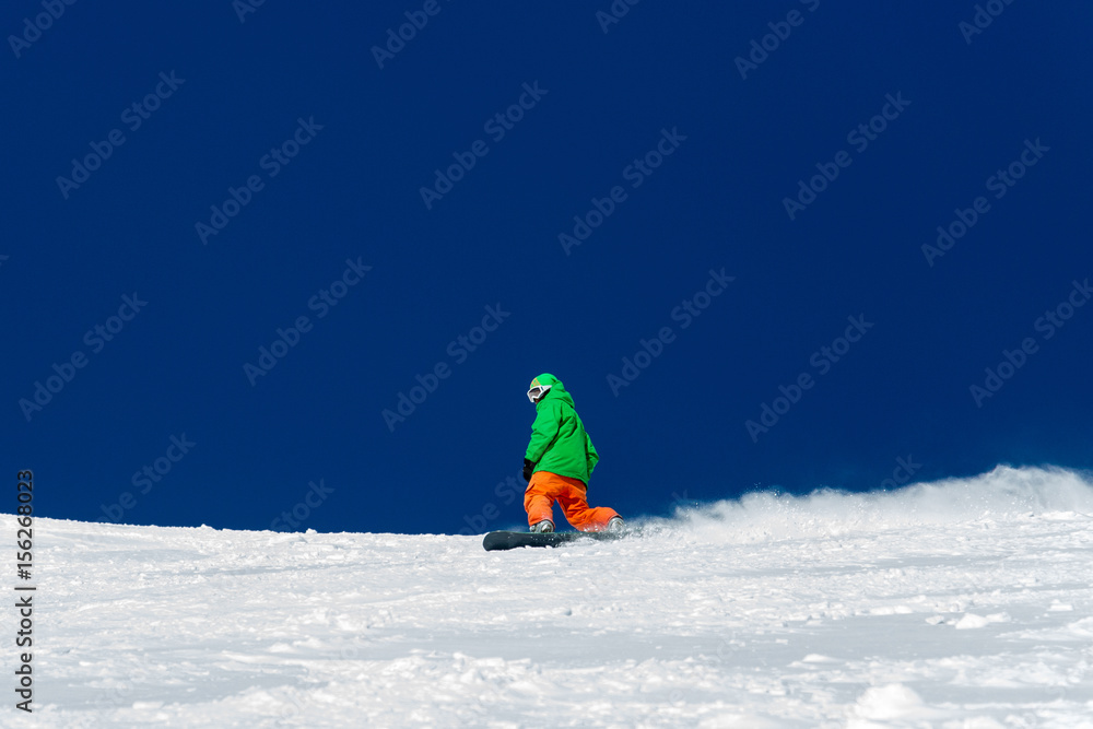 Male snowboarder snowboarding on fresh snow on ski slope on Sunny winter day in the ski resort in Georgia. Travel adventure concept. space for text