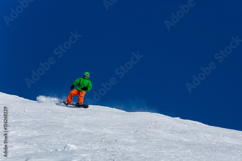 Male snowboarder snowboarding on fresh snow on ski slope on Sunny winter day in the ski resort in Georgia. Travel adventure concept. space for text