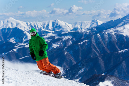 Male snowboarder snowboarding on fresh snow on ski slope on Sunny winter day in the ski resort in Georgia. Travel adventure concept. space for text