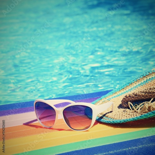 Sunglasses, lilo and hat on the water in hot sunny day. Summer background for traveling and vacation. Holiday idyllic.