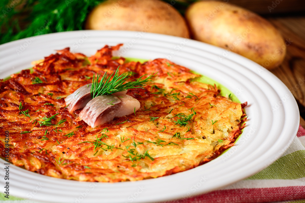 Potato rosti with dill and salted herring in plate on wooden table. Potato rosti with dill and salted herring in plate on wooden table.