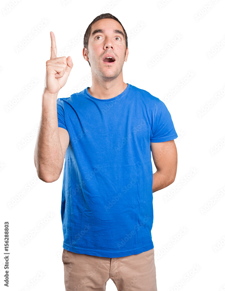 Naklejka premium Confident young man pointing up against white background