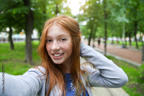Girl walks in the park and makes selfie. Instagram
