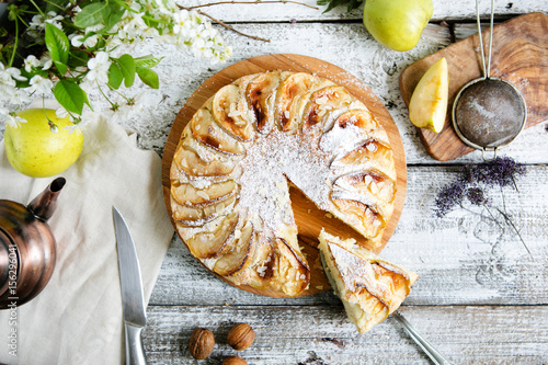 Apple pie on a wooden table with a teapot, top view, flat