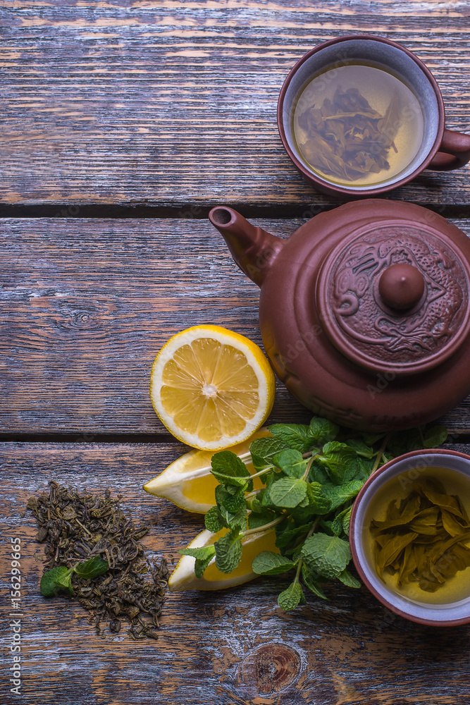 Green Tea cup, tea pot and slices of lemon, ginger, mint, on wooden background Green Tea cup, tea pot and slices of lemon, ginger, mint, on wooden background
