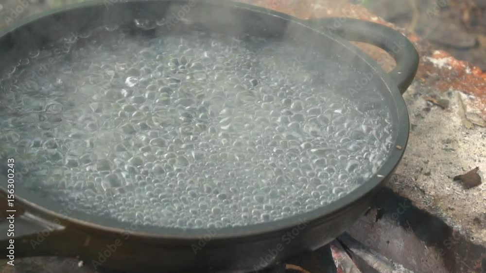 Boiling water bubble in pan heating on bonfire. Cooking food on real fire. Boiling water bubble in pan heating on bonfire. Cooking food on real fire.
