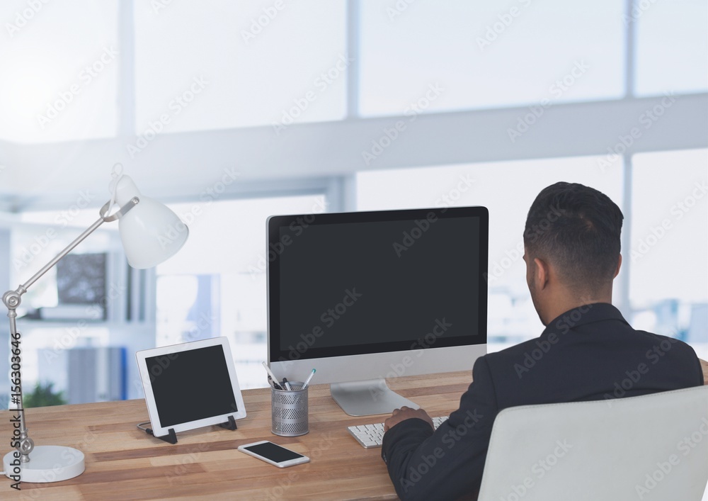 Businessman on computer in large bright office Businessman on computer in large bright office